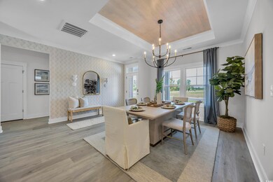 Dining area featuring baseboards, a chandelier, a raised ceiling, light wood-style floors, and crown molding