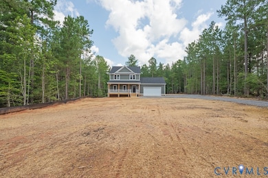 View of front of home featuring a garage, driveway, a forest view, and a porch