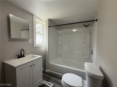 Full bath with vanity, shower / bathtub combination, and wood finished floors
