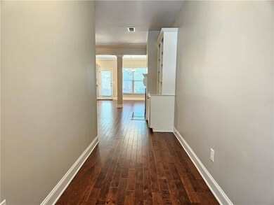Hall featuring dark wood-type flooring, baseboards, and a chandelier