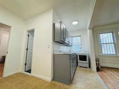 Kitchen with gray cabinetry, light countertops, white range, radiator, and light tile patterned flooring