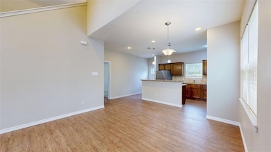Kitchen featuring a center island, hanging light fixtures, light wood-type flooring, freestanding refrigerator, and open floor plan