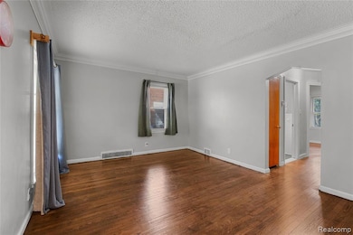 Unfurnished room featuring arched walkways, ornamental molding, dark wood-style flooring, and a textured ceiling