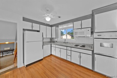 Kitchen featuring white cabinetry, white appliances, a baseboard heating unit, backsplash, and light hardwood floors