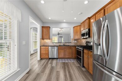 Kitchen featuring appliances with stainless steel finishes, decorative backsplash, brown cabinetry, dark wood finished floors, and recessed lighting
