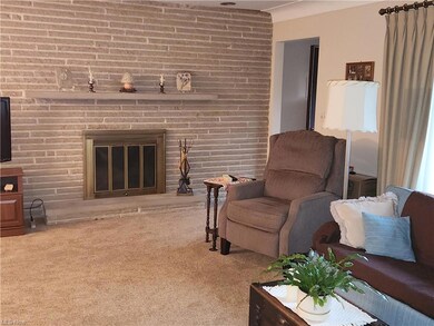 Living room with light colored carpet, brick wall, and a brick fireplace