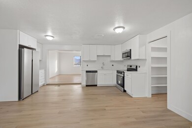 Kitchen featuring white cabinets, stainless steel appliances, light countertops, a textured ceiling, and light wood-style flooring