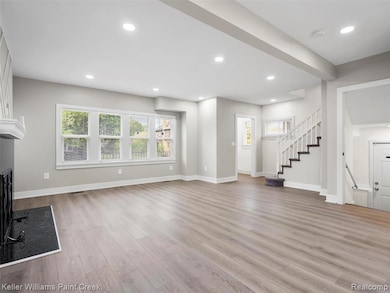 Unfurnished living room with stairs, a large fireplace, light wood-style flooring, and recessed lighting