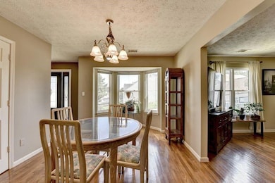 Dining space featuring a textured ceiling, a chandelier, light wood-style floors, and plenty of natural light