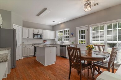 Kitchen with appliances with stainless steel finishes, white cabinets, a center island, a sink, and light stone countertops