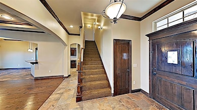 Foyer featuring ornamental molding, arched walkways, stone tile flooring, and stairs