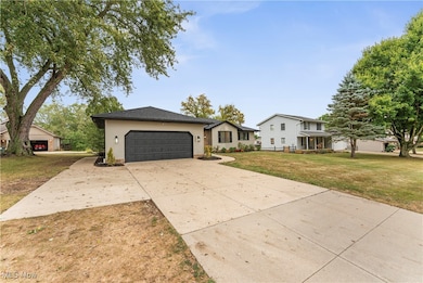 View of front of property featuring concrete driveway, a front yard, and an attached garage