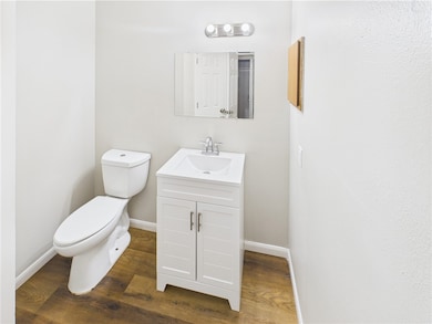 Half bathroom with toilet, vanity, wood finished f