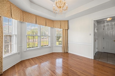 Unfurnished room with a chandelier, wood finished floors, and a tray ceiling