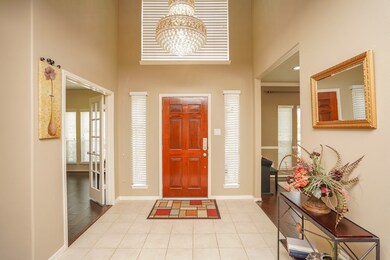 This view has the study/office to the left, and living/dining room to the right. Notice the gorgeous multi-tiered expensive chandelier, which stays with the home.