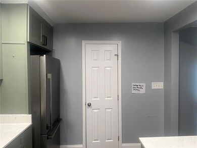 Kitchen with freestanding refrigerator, light stone countertops, and baseboards