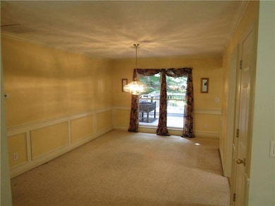 Unfurnished room featuring a decorative wall, crown molding, carpet, and a wainscoted wall