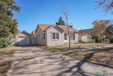View of front of home with driveway, an outbuilding, stucco siding, roof with shingles, and crawl space