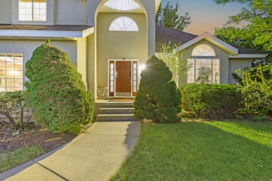 Doorway to property with stucco siding, a shingled roof, and a lawn