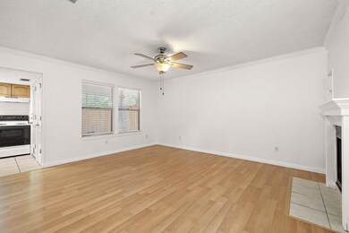 Unfurnished living room featuring crown molding, a textured ceiling, light wood-style flooring, a fireplace with flush hearth, and a ceiling fan