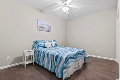 Bedroom with a ceiling fan, baseboards, and wood f