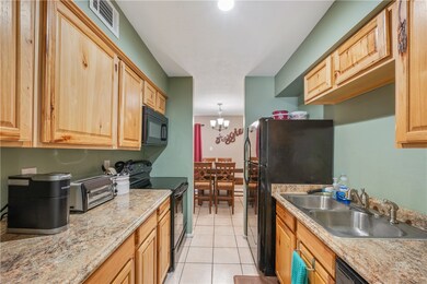 Kitchen with black appliances, light tile patterne