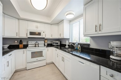 Kitchen with white appliances, a tray ceiling, a s