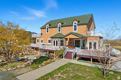 View of south side of home with stucco siding, a deck, a lawn, stairs, and a balcony.