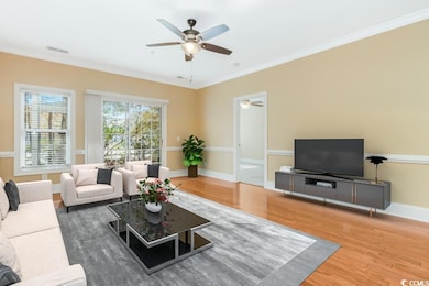 Living area with crown molding, wood finished floo