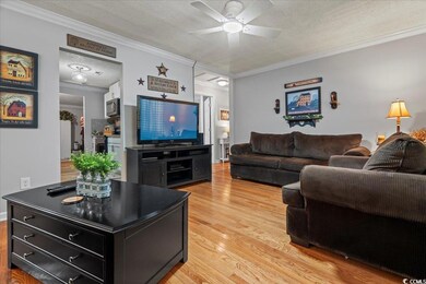Living room featuring crown molding, light wood-st