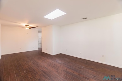 Spare room with a skylight, dark wood-style flooring, and ceiling fan