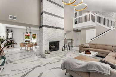 Living room with light tile patterned floors, a fireplace, a chandelier, and a high ceiling