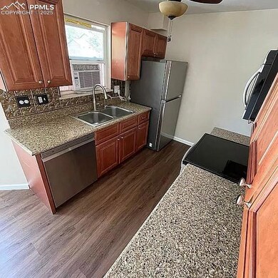 Kitchen with appliances with stainless steel finishes, dark wood-style flooring, ceiling fan, brown cabinetry, and cooling unit
