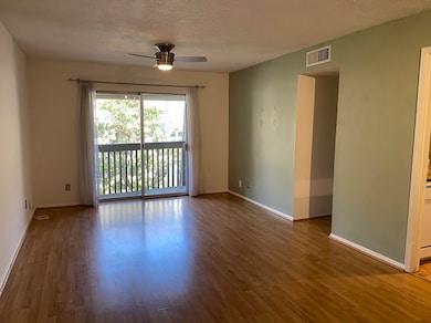 Open living space with ceiling fan, and wood finished floors