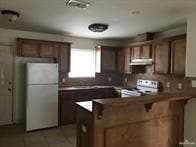 Kitchen featuring freestanding refrigerator, a peninsula, a breakfast bar, under cabinet range hood, and range