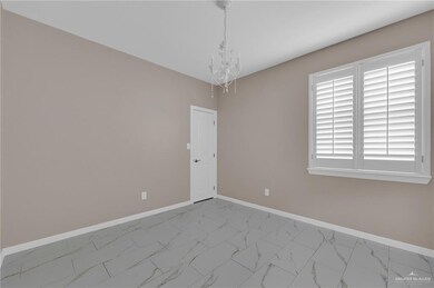 Spare room with marble finish flooring, a chandelier, and baseboards