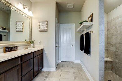 PRIMARY BATH  Tasteful oversized tile stretches from the floor into the walk in Roman shower--contemporary with no shower door.  Dual sinks and a large walk in closet.