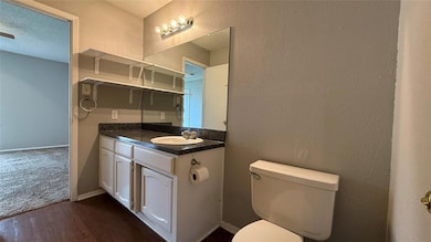 Bathroom with toilet, vanity, wood finished floors