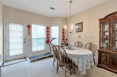 Dining area with a chandelier, carpet flooring, a wainscoted wall, and healthy amount of natural light