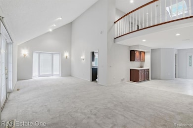 Unfurnished living room featuring high vaulted ceiling, light colored carpet, and recessed lighting
