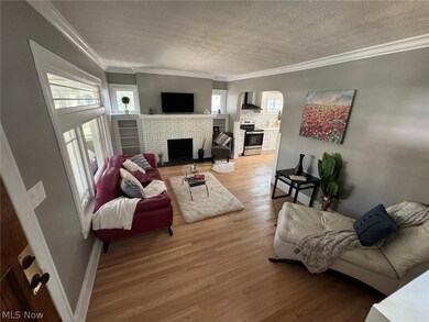 Living room featuring a fireplace, wood-type flooring, crown molding, and a textured ceiling
