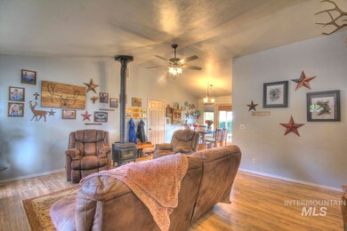 Living area with a wood stove, wood finished floors, vaulted ceiling, a ceiling fan, and a chandelier
