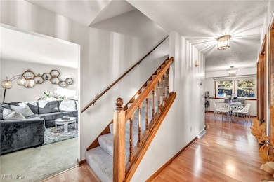 Center hall stairs featuring wood finished floors and a chandelier