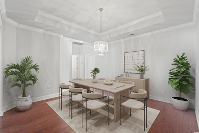 Dining space featuring a raised ceiling, dark wood-style flooring, and crown molding