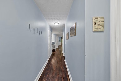 Hall featuring a textured ceiling, baseboards, and