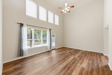 Unfurnished room with a high ceiling, wood finished floors, and ceiling fan