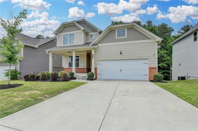 Craftsman house with brick siding, a front lawn, driveway, and a porch