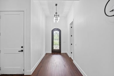 Entryway with a chandelier, dark wood-style floor