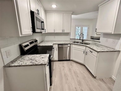 Kitchen with white cabinetry, light wood-style flo
