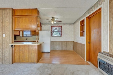 Kitchen featuring wallpapered walls, light countertops, wood walls, wainscoting, and freestanding refrigerator